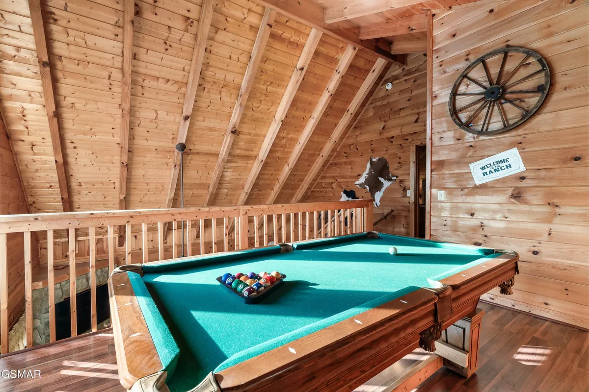 A warmly lit game loft featuring a pool table, wooden walls, and a wagon wheel as rustic decor. The inviting venue encourages socializing, friendly competition, and memorable evenings with friends or family.